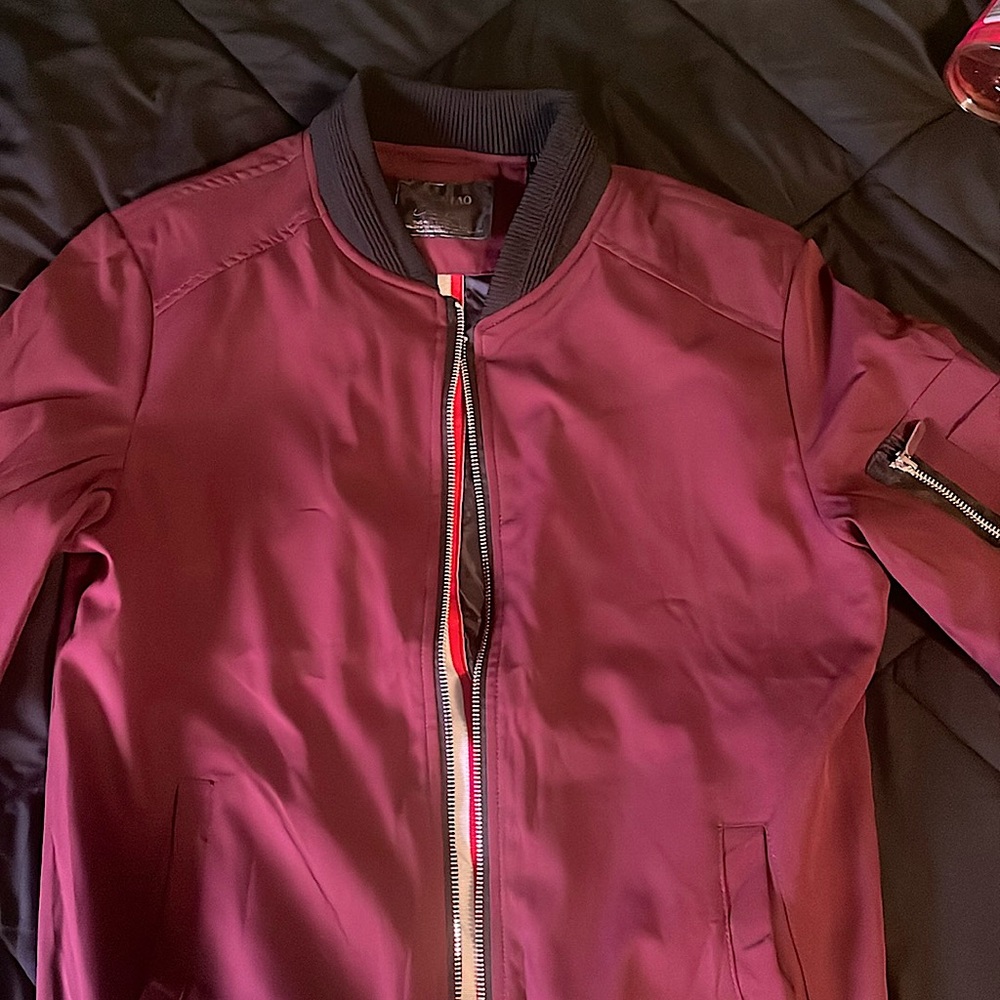 A burgundy colored bomber jacket.